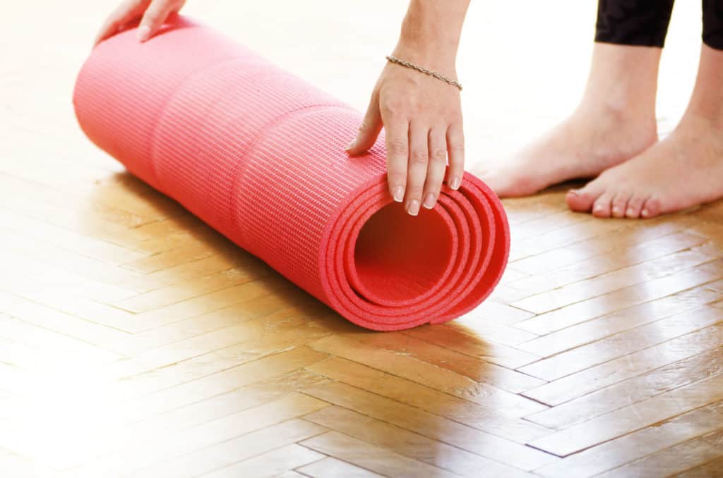 Female Hands Unrolling Yoga Mat Before group fitness class