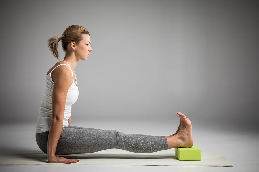 woman practicing yoga with a block for injury prevention. 