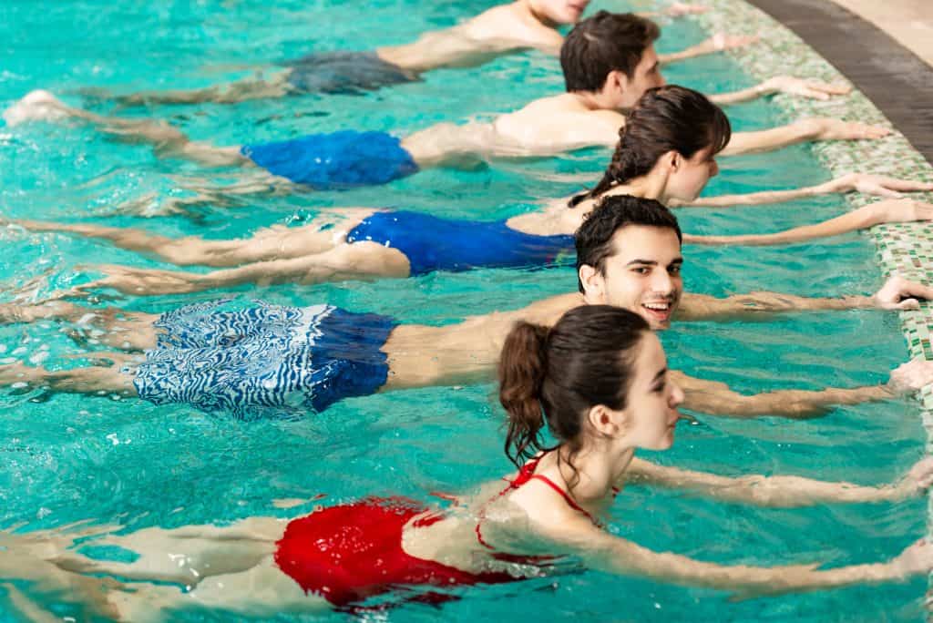 people in an aquatic exercise class performing kicking at the wall. a decorative image in an article about pool exercise ideas