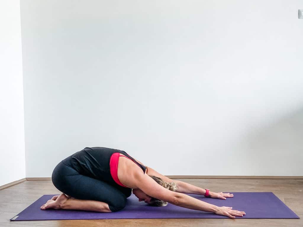 woman on a yoga mat in childs pose for lower back stretching