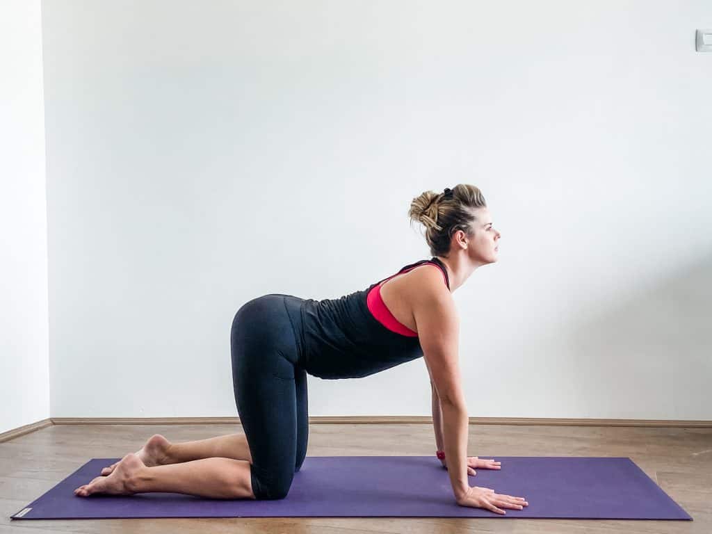 woman doing cow pose, spinal extension on a yoga mat. 
