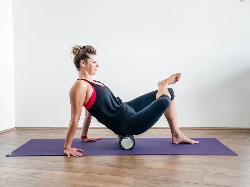 woman demonstrating foam rolling for glutes - hip flexibility exercises