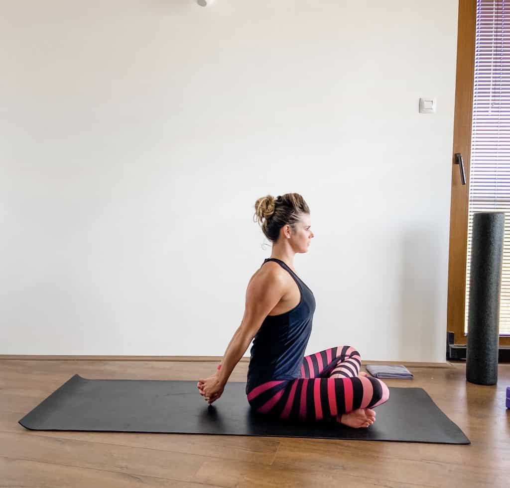 woman seated on a yoga mat demonstrating a shoulder extension stretch